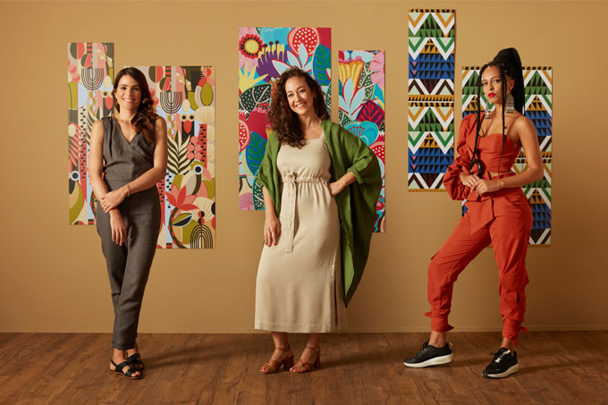 Decoradoras Naia Ceschin, Julia Fontes e Criola em frente a suas estampas