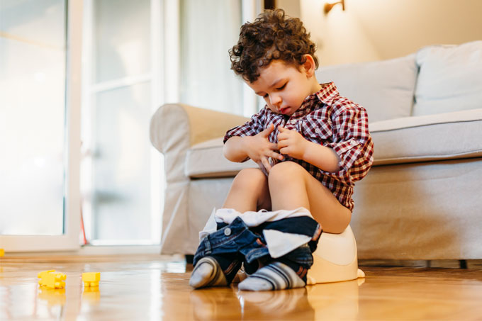 Menino pequeno no penico olhando as mãos