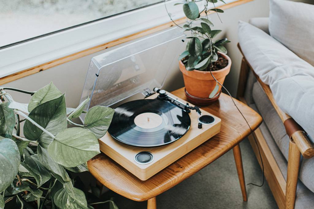 fotografia de toca disco com caixa de som embutida na sala com plantas e um sofá
