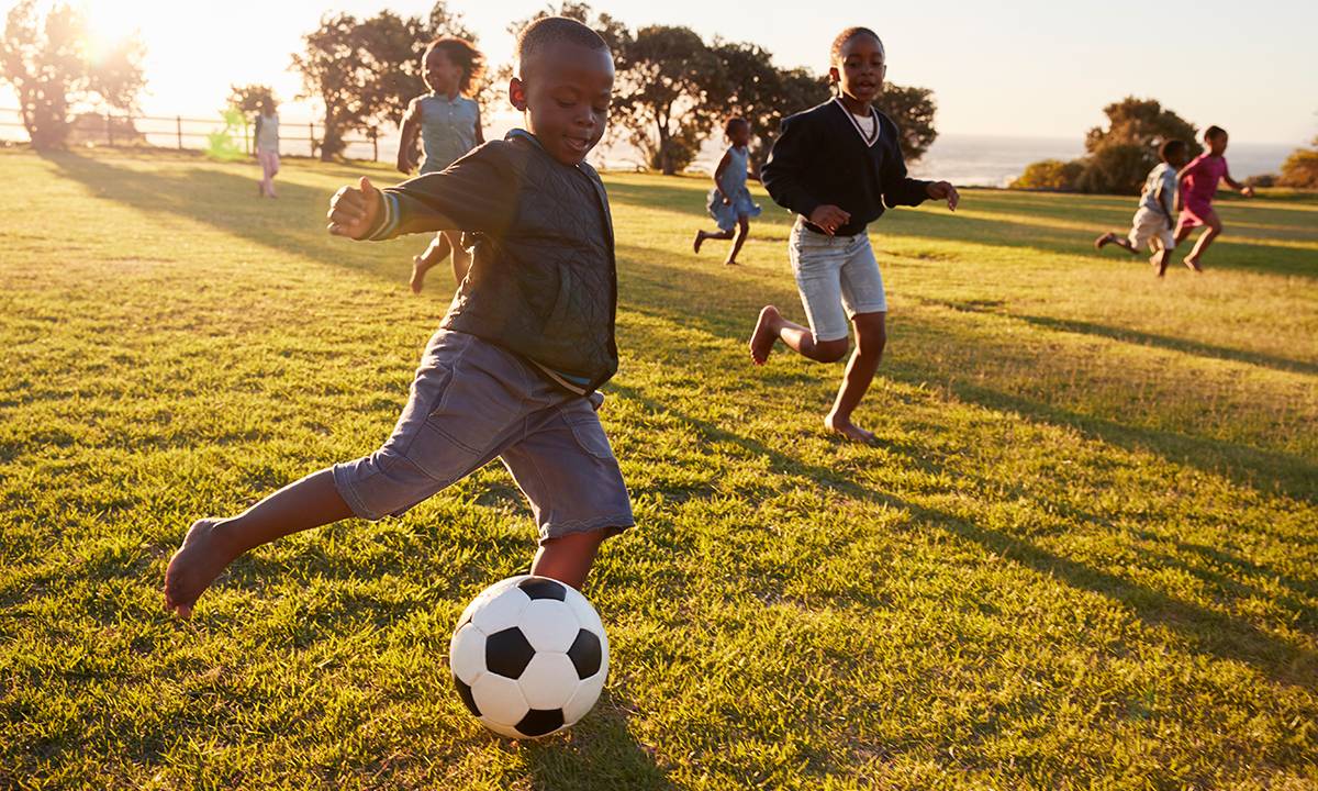 crianças correndo jogando futebol