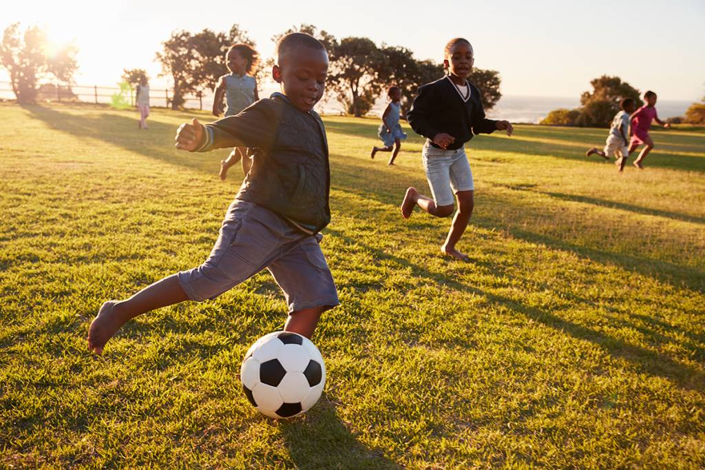 crianças correndo jogando futebol